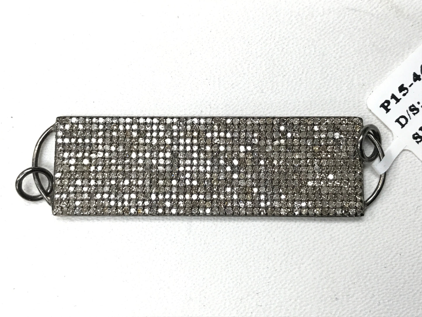 A rectangular diamond pendant with a silver setting and a chain loop at the back, tagged with 'P15-4479'.