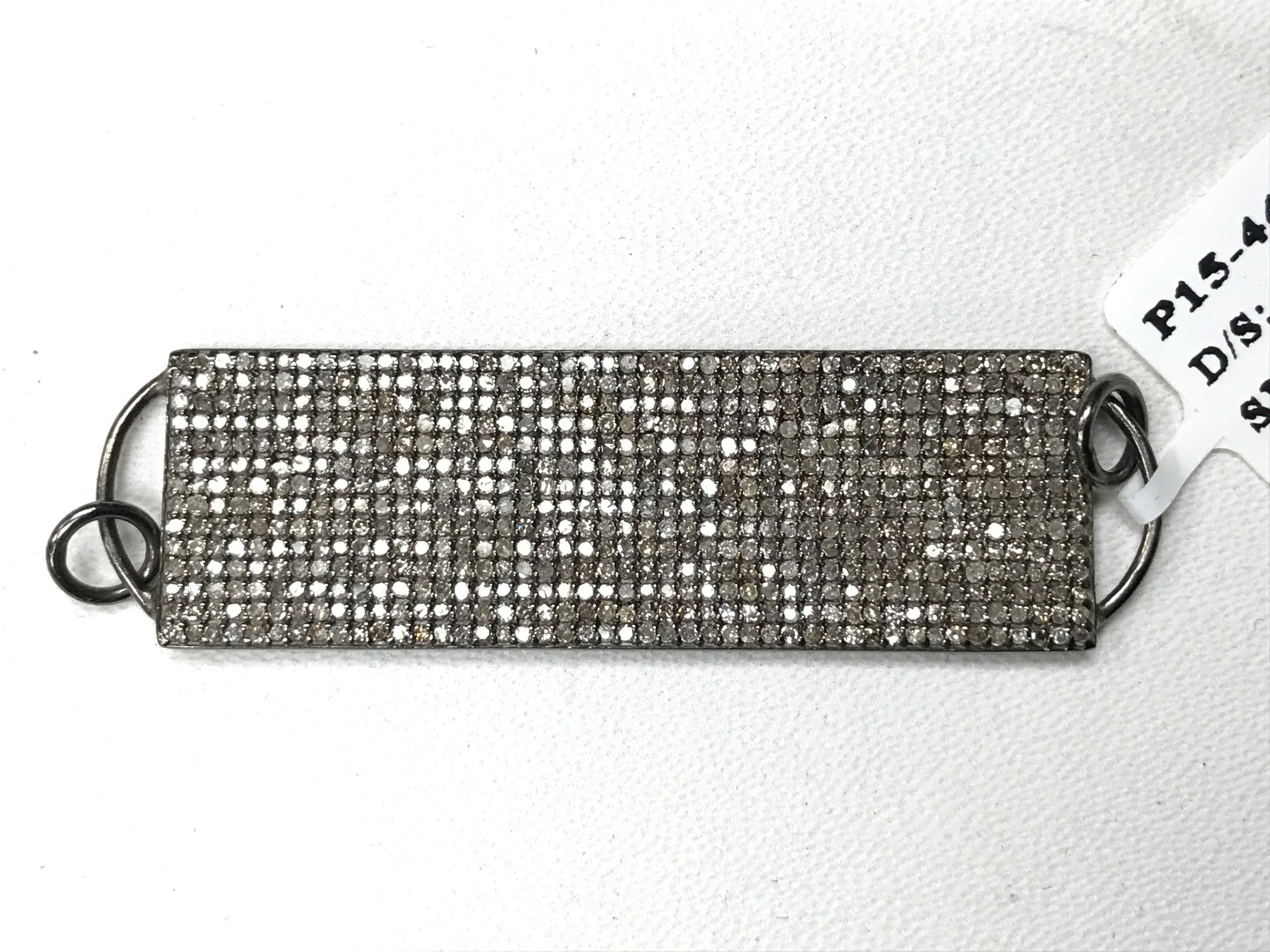 A rectangular diamond pendant with a silver setting and a chain loop at the back, tagged with 'P15-4479'.